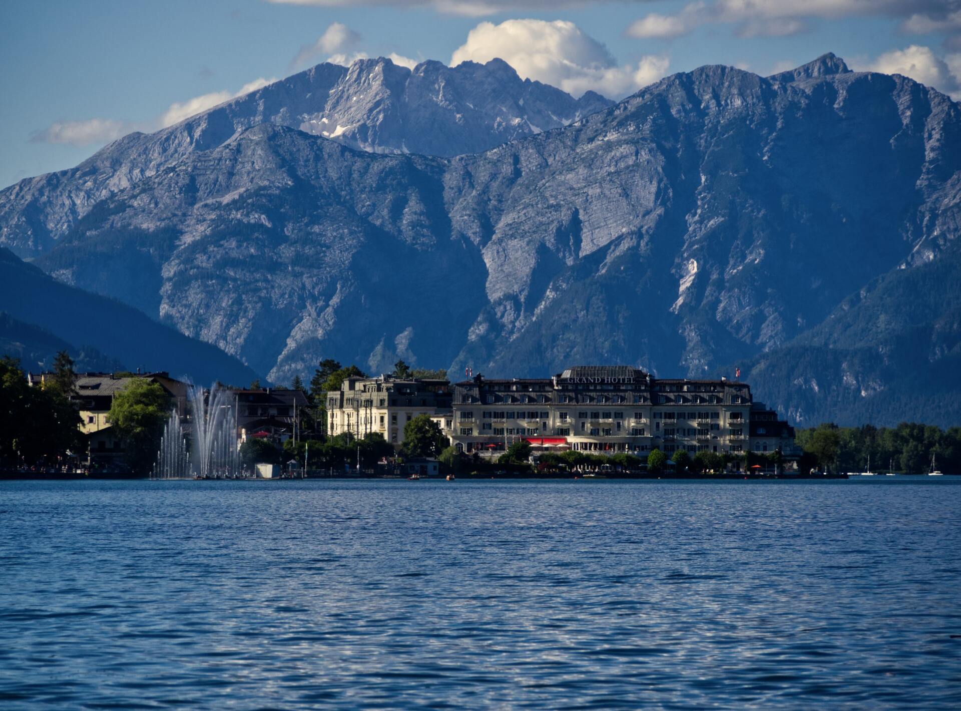 Hinter einer Stadt am Seeufer erheben sich schneebedeckte Berge jenseits des blauen Wassers.