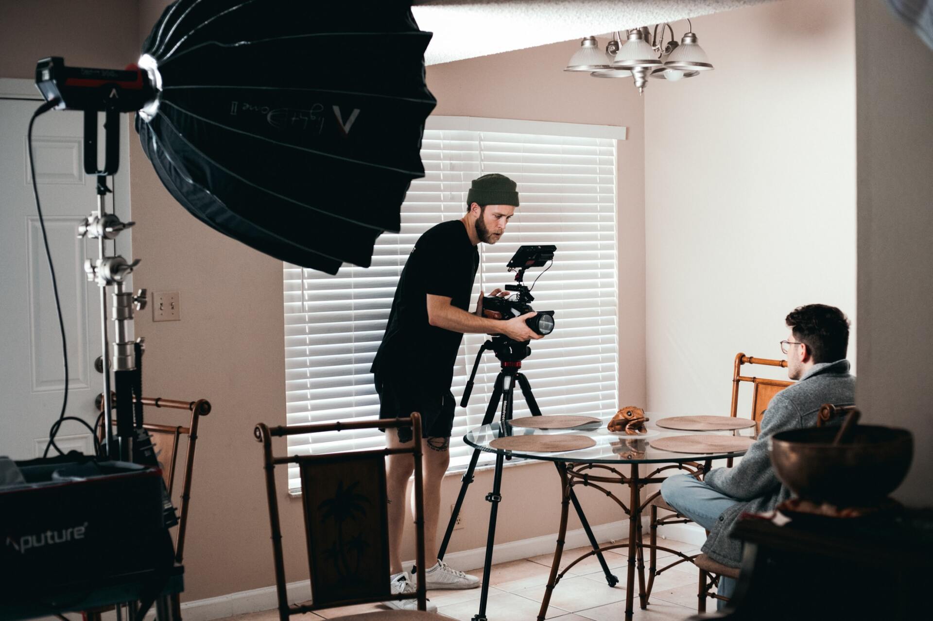 Vídeo Corporativo Um homem está tirando a foto de um homem sentado à mesa de uma sala de estar.
