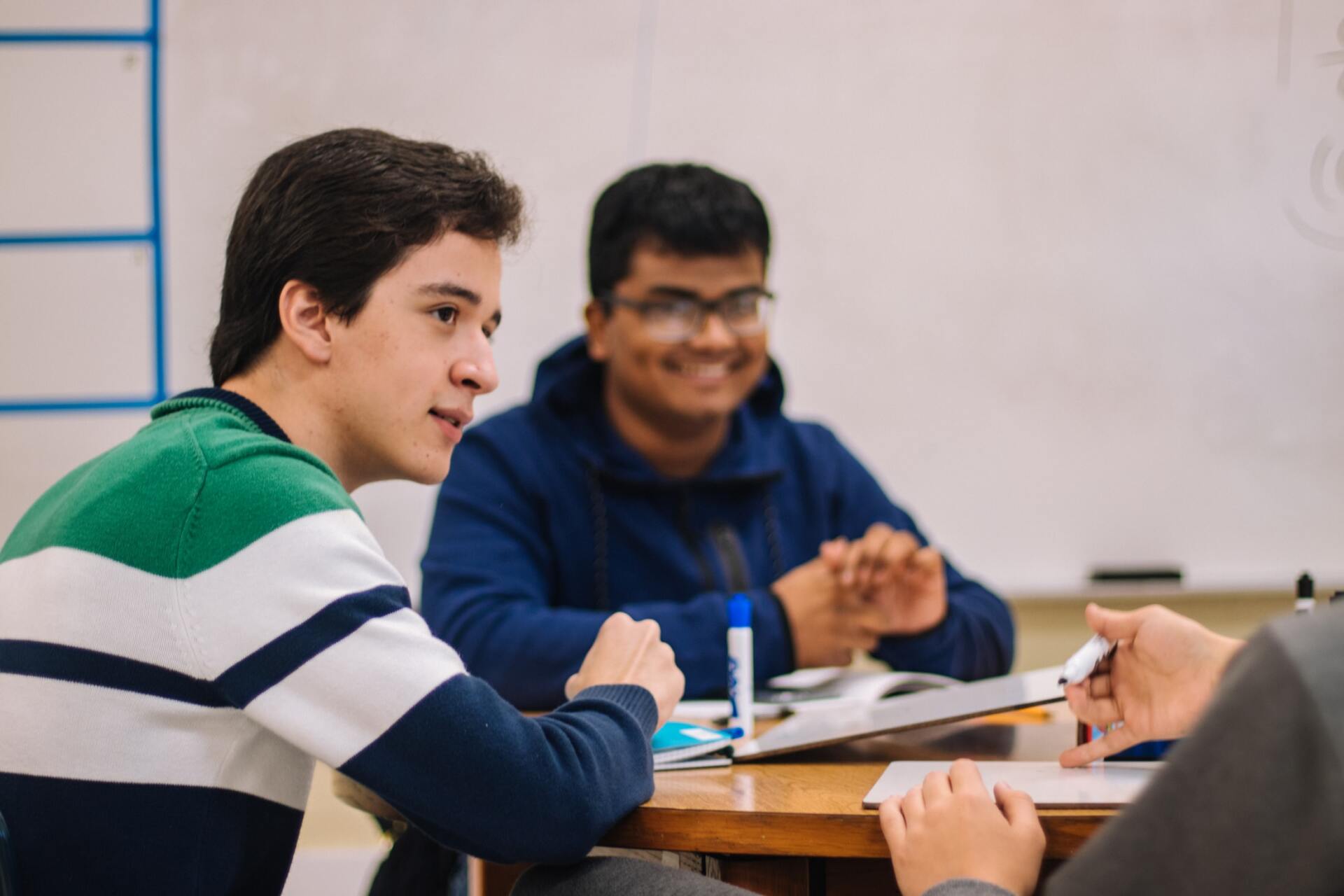 A group of young men are sitting at a table in a classroom.