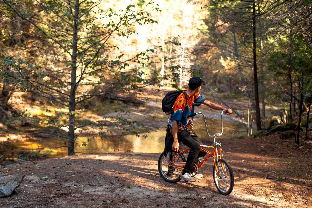 A man is riding a bike on a dirt road in the woods.