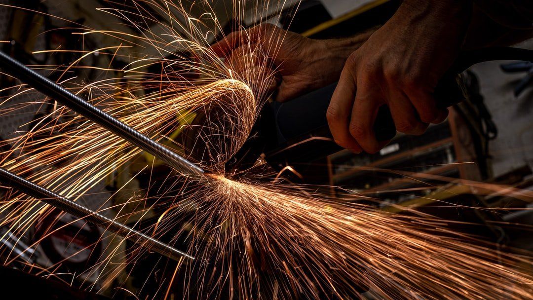 A person is grinding a piece of metal with a grinder.