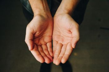 Two open hands, palms facing up, against a dark background.