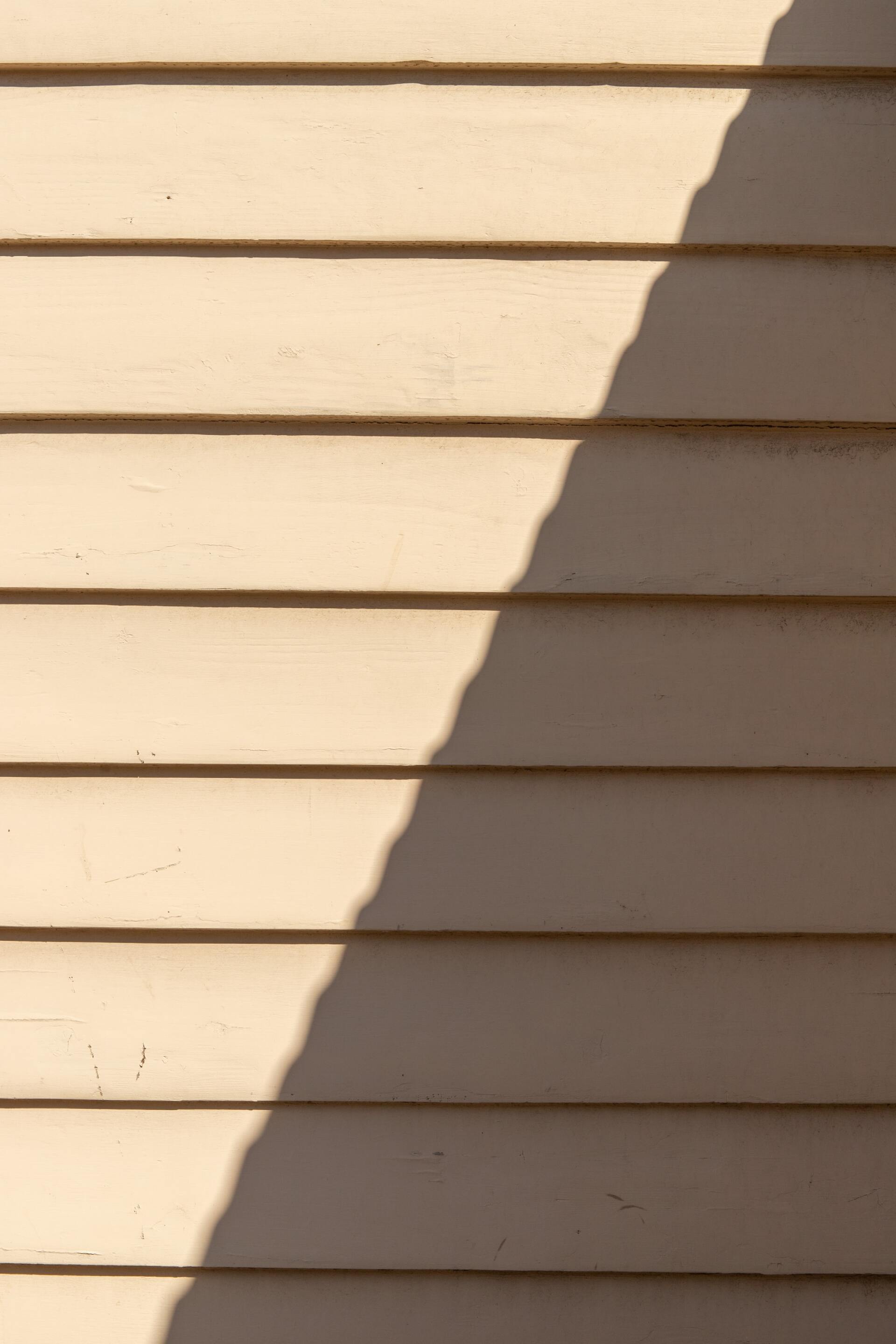 Cream-colored clapboard siding with a dark shadow running diagonally.