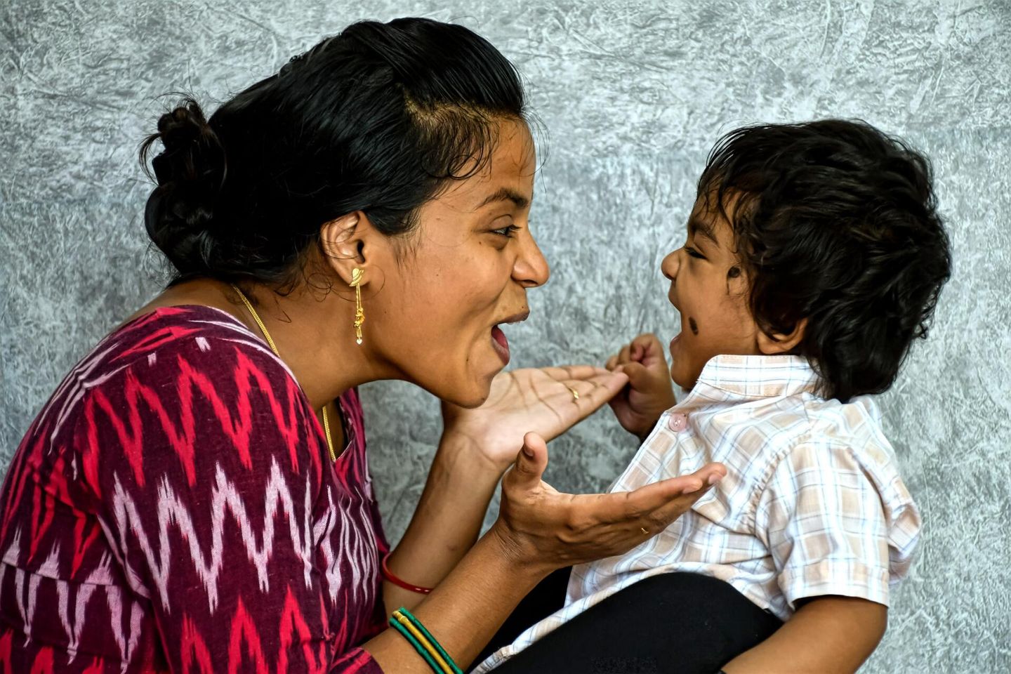 A woman is holding a baby in her arms and the baby is licking the woman 's face.