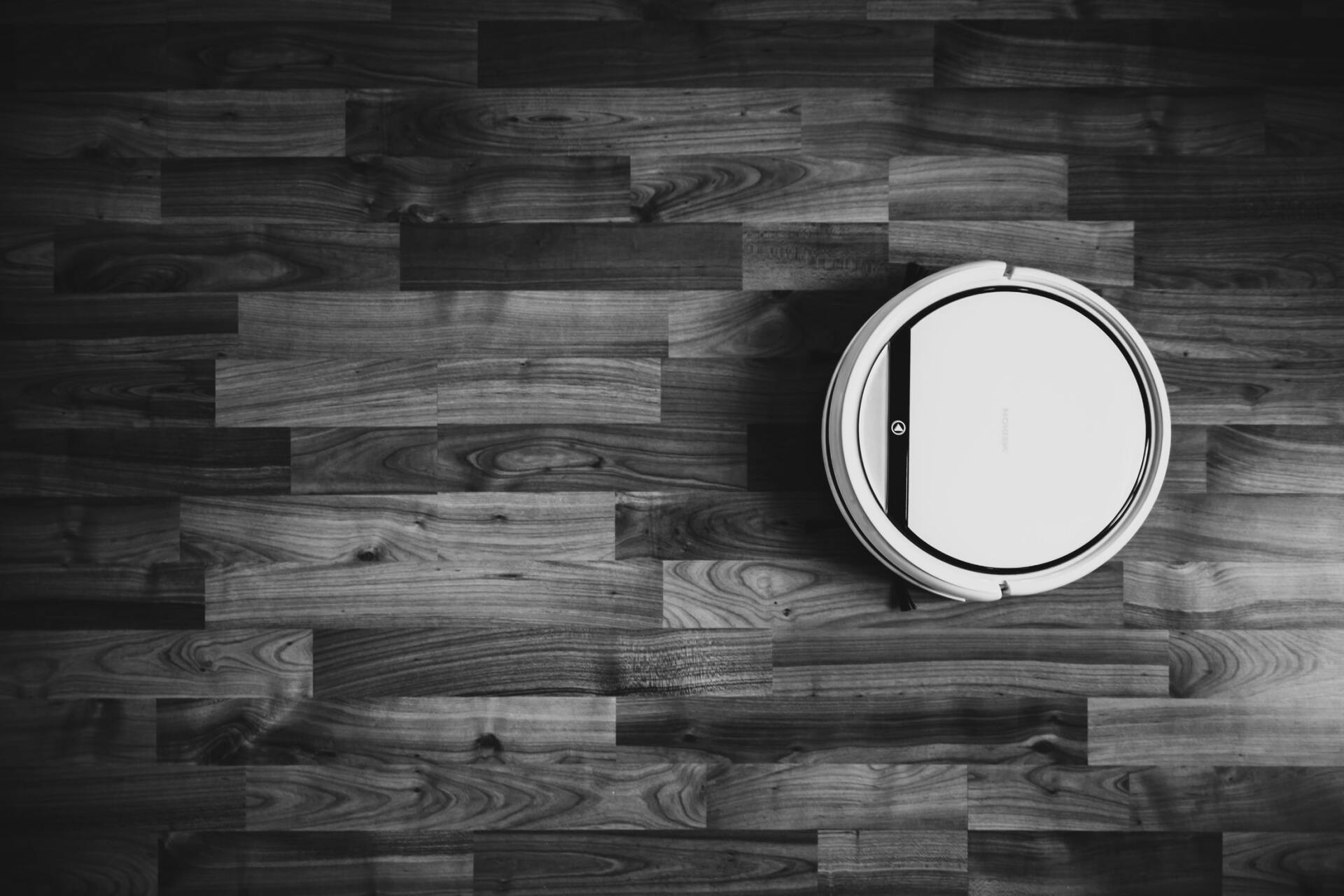 A black and white photo of a vacuum cleaner on a wooden floor.