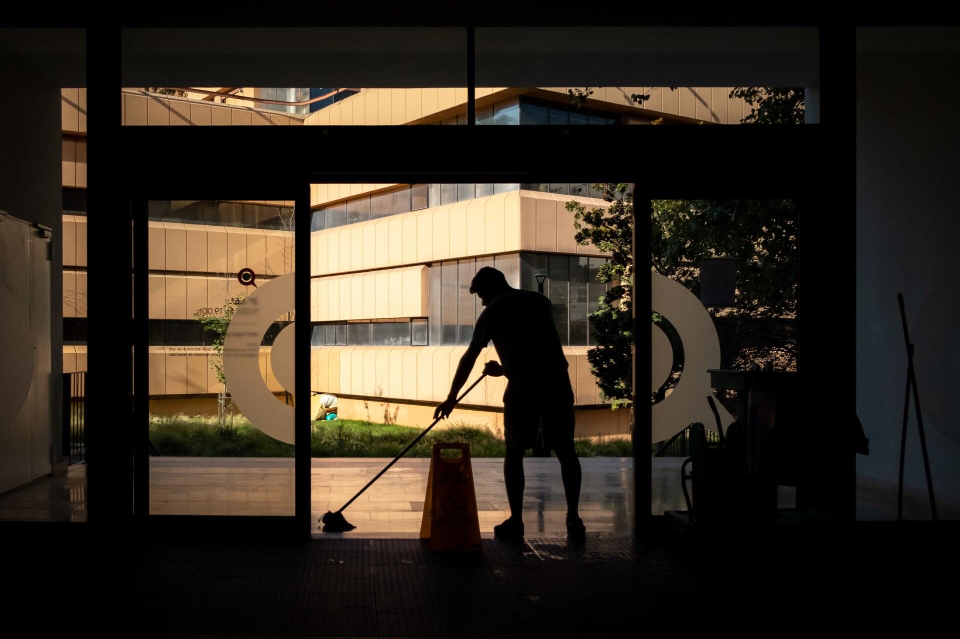 A man is cleaning the floor of a building with a mop.