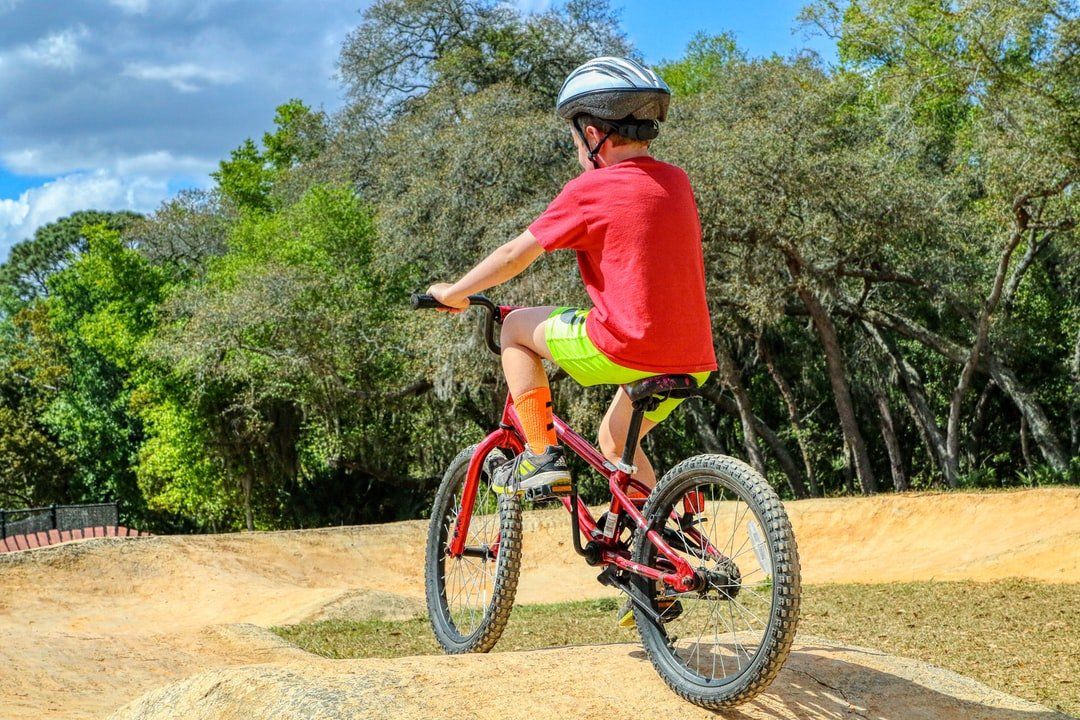 A young boy is riding a bike on a dirt track.