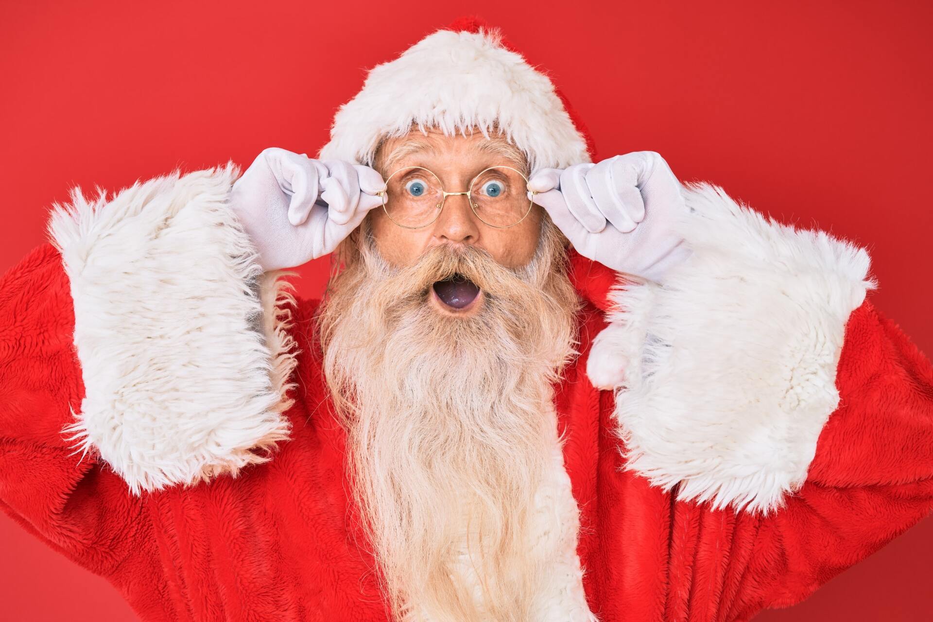 A surprised santa claus is covering his eyes with his hands