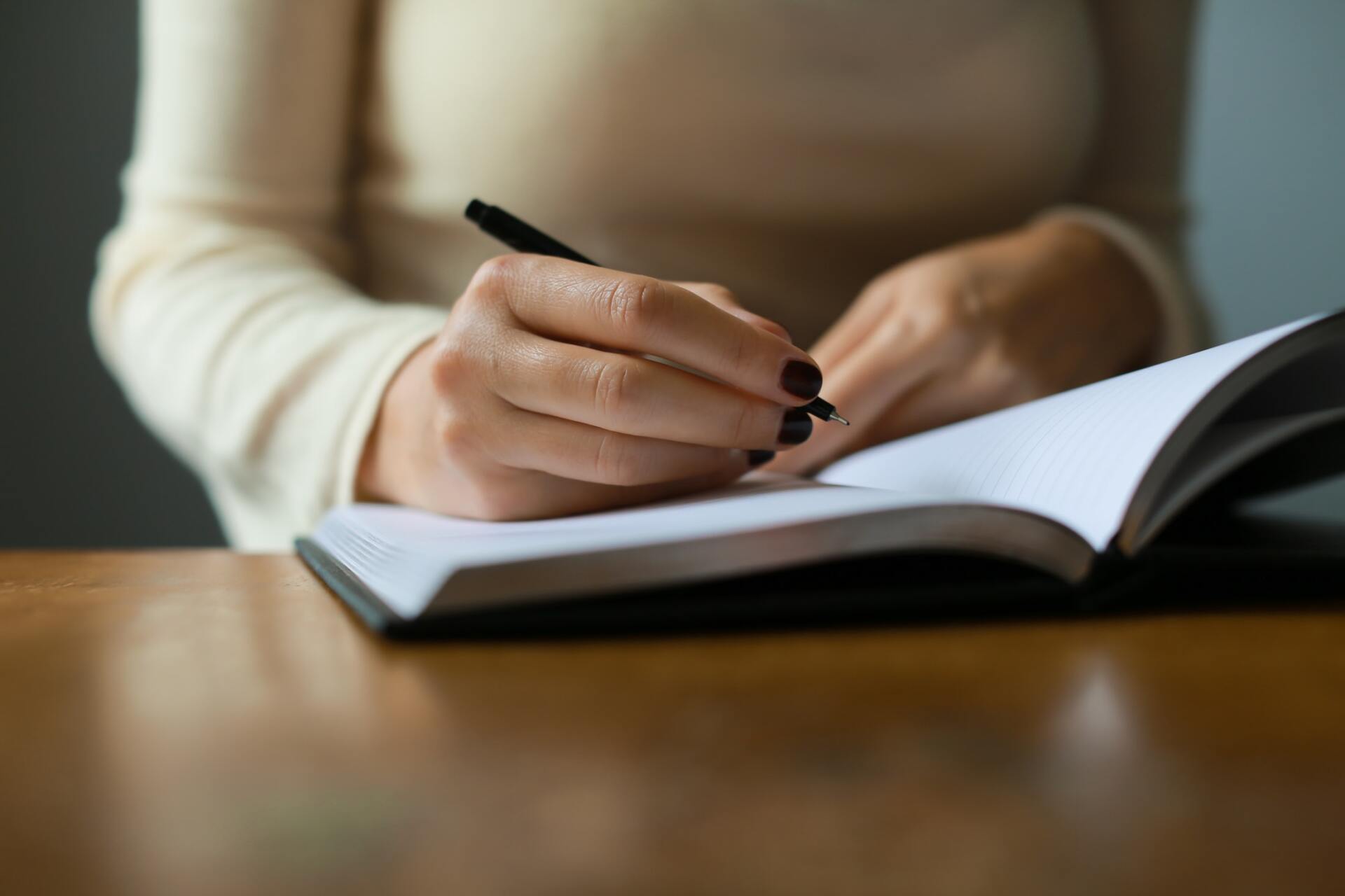 A woman is writing in a notebook with a pen.