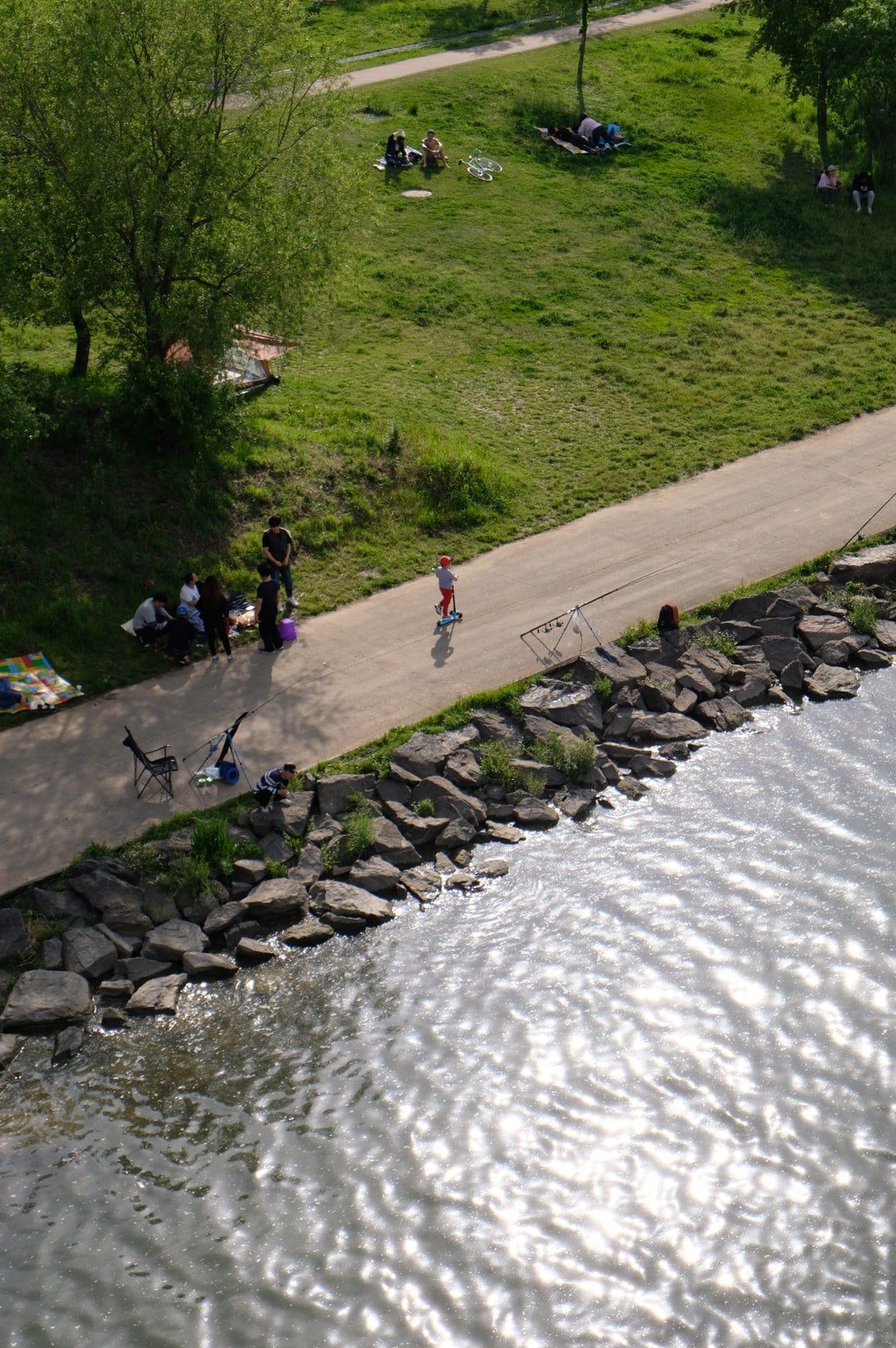 A group of people are walking along a path next to a body of water.
