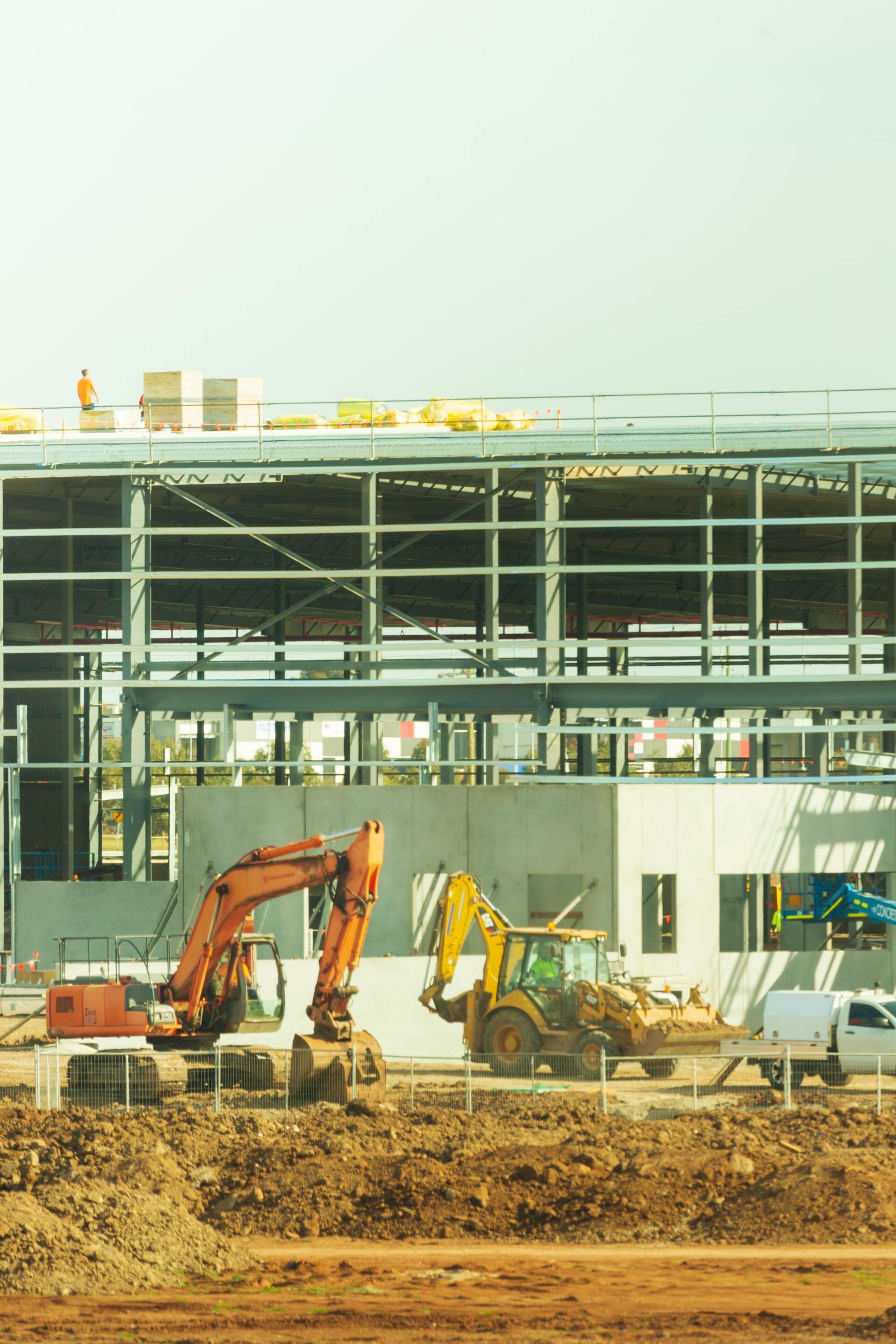 A large building is being built with a lot of machinery in front of it.