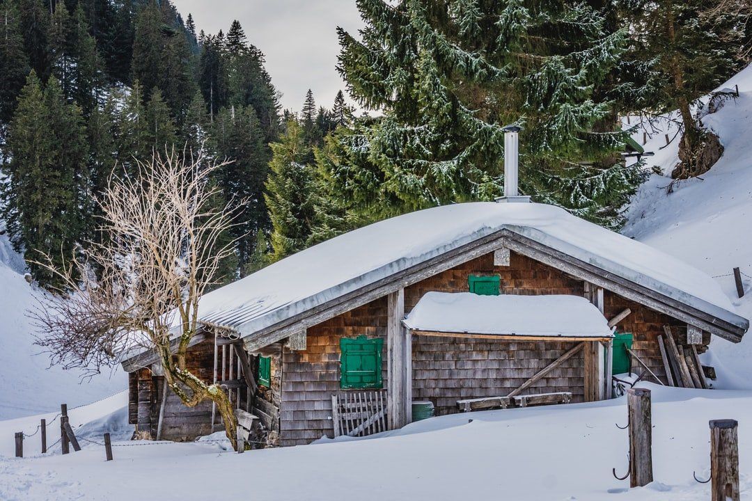 Schneebedeckte Holzhütte in einer bewaldeten Berglandschaft