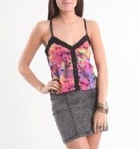 Woman wearing a colorful floral camisole and gray skirt, standing with one hand on her hip.