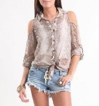 Woman wearing a light patterned blouse and denim shorts, standing against a white background.