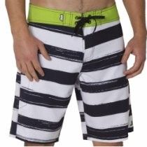 Black-and-white striped board shorts with neon green waistband and black drawstring on a person’s waist