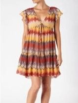 Woman wearing a multicolor patterned sleeveless dress, standing against a white background