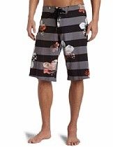 Black striped knee-length board shorts with floral prints, shown on a model standing barefoot.