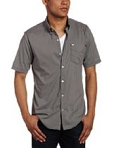 Man wearing a gray short-sleeve button-up shirt with dark jeans, standing against a white background