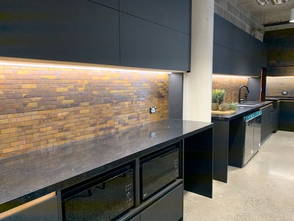 A Kitchen With Black Cabinets and a Brick Wall — High Kraft Kitchens and Joinery in Berkeley, NSW