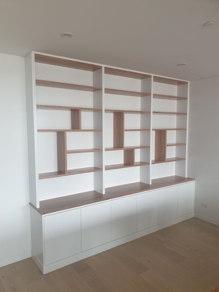 A Large White Bookshelf With Wooden Shelves in a Living Room — High Kraft Kitchens and Joinery in Berkeley, NSW
