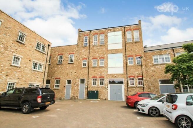 A row of cars are parked in front of a large brick building.
