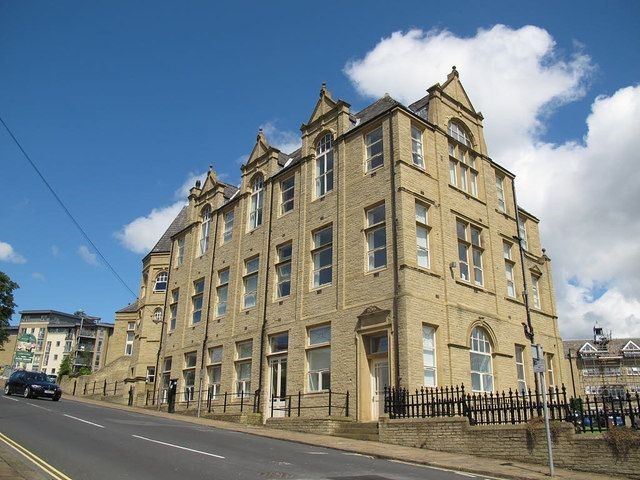 A large building with a lot of windows is on the side of a road