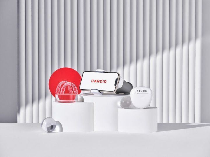 White cosmetic jars and a red compact on white pedestals in a minimalist studio setting