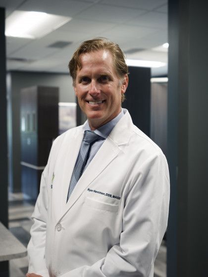 Doctor in a white coat smiling in a hospital hallway