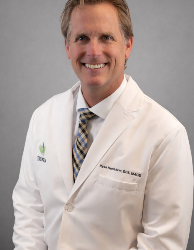 Doctor in a white coat smiling in a hospital hallway