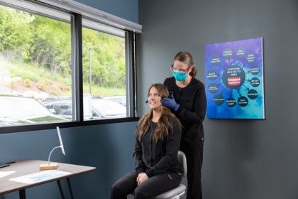 Woman getting a facial treatment in a modern spa room while a technician stands behind her
