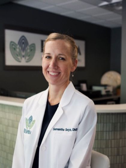 Smiling medical professional in a white coat standing in a clinic office