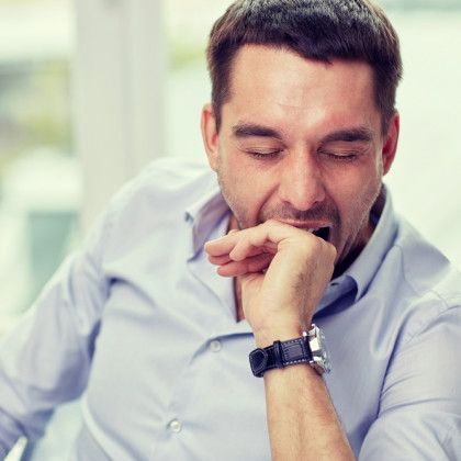 Man in a light blue shirt resting his chin on his hand, eyes closed in thought or fatigue