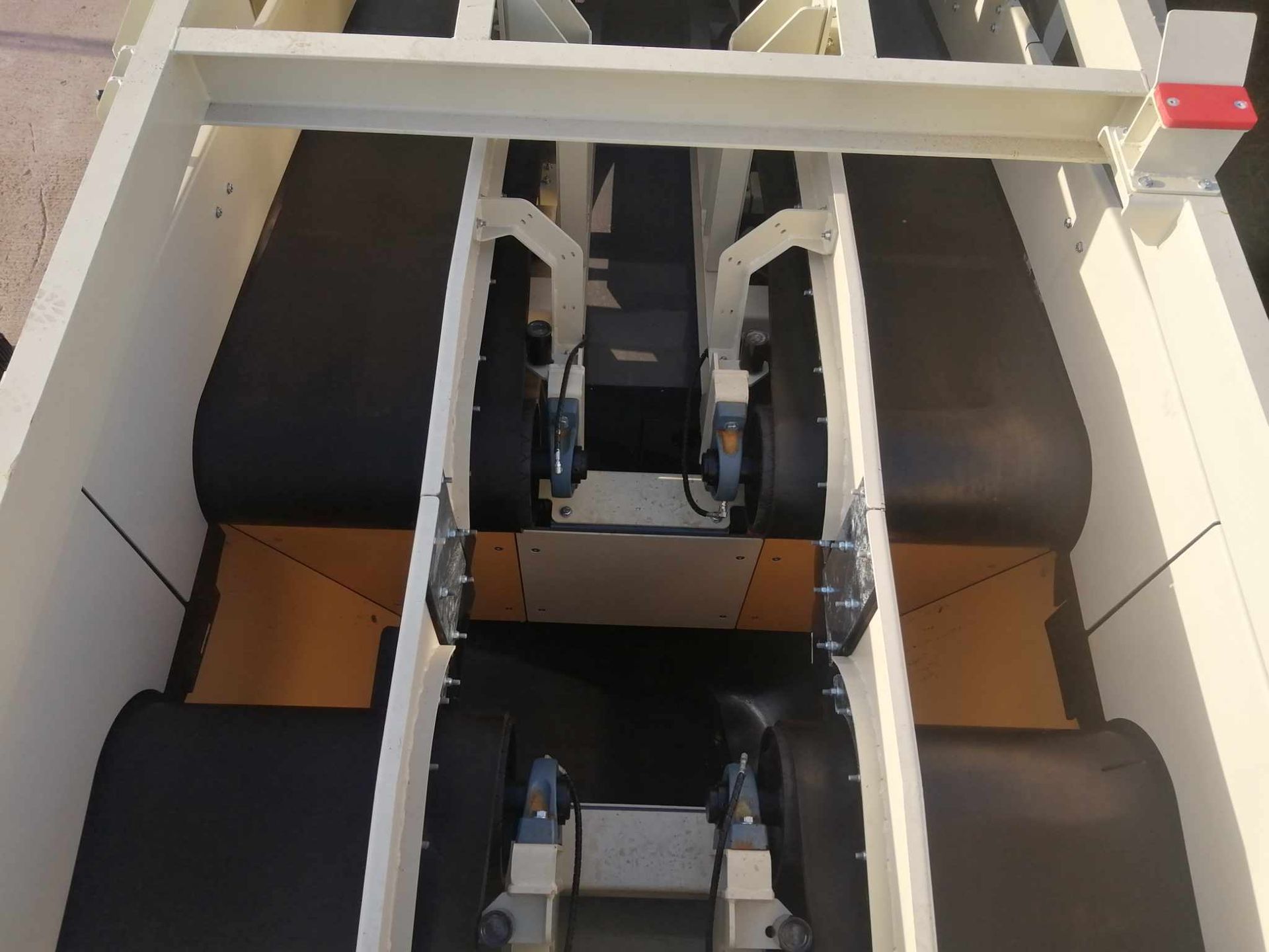 Overhead view of a conveyor belt system with multiple black belts and a white frame.