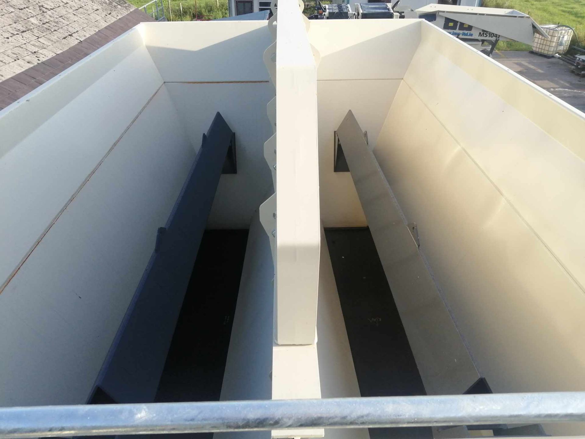 Inside view of a large white container with two long black dividers and support beams.