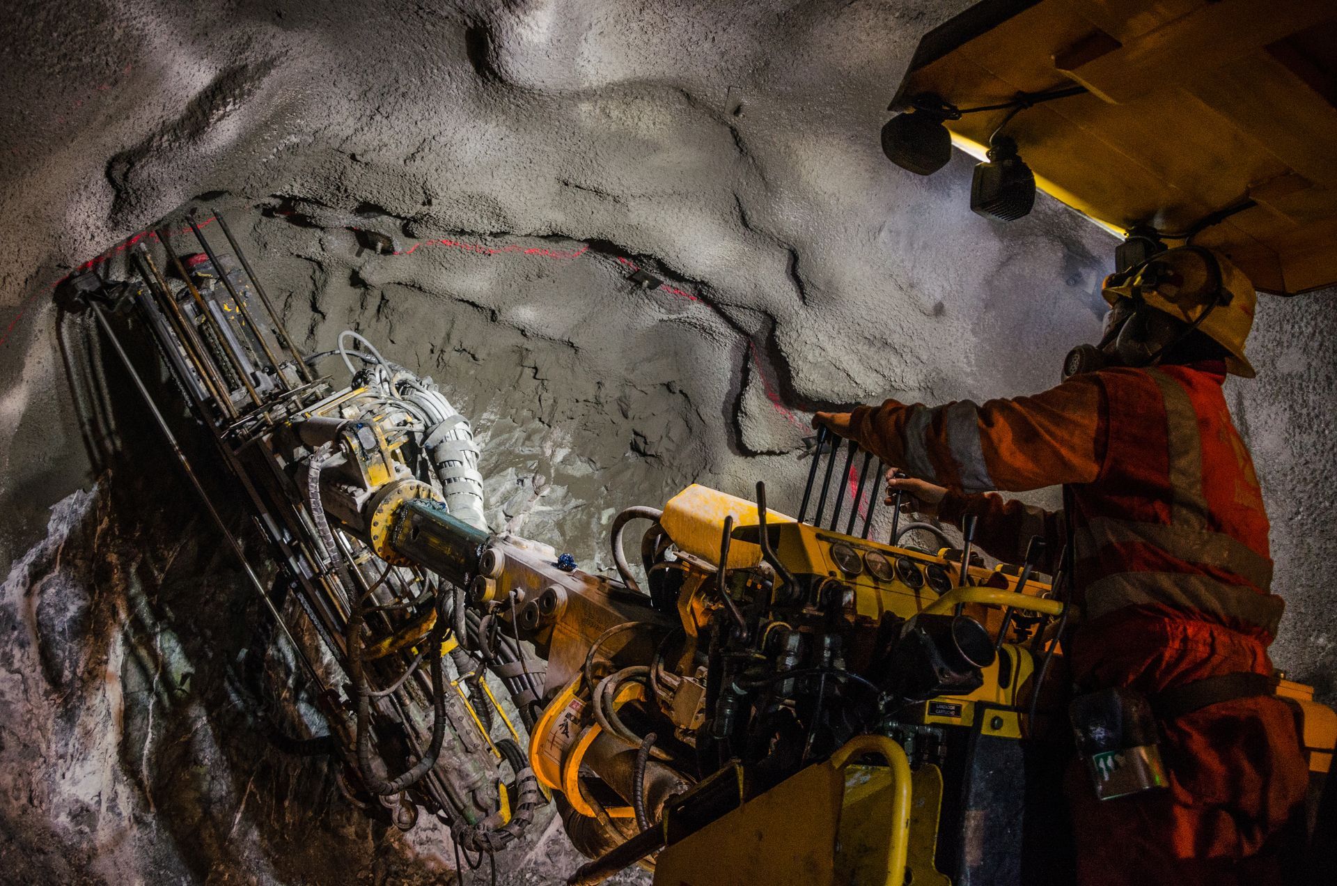 Miners operating drilling equipment in a rocky underground tunnel