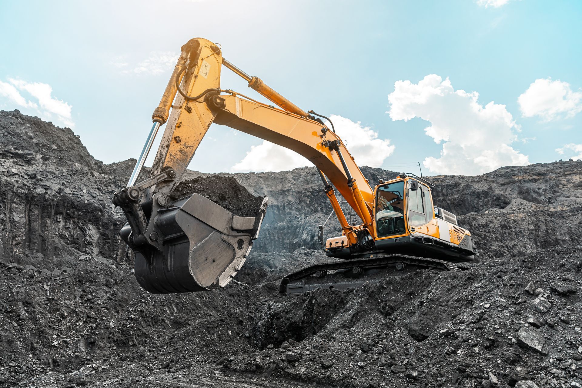 A big yellow quarry mining truck is at the work site, loading coal into the body of the truck. A big yellow quarry mining truck is at the work site, loading coal into the body of the truck.