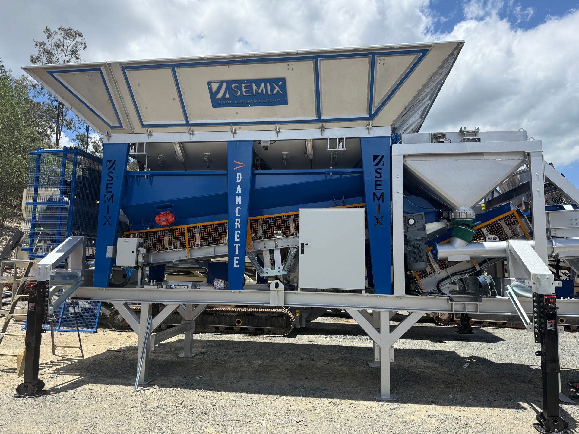 Blue and white Semix concrete mixing machine on a construction site.