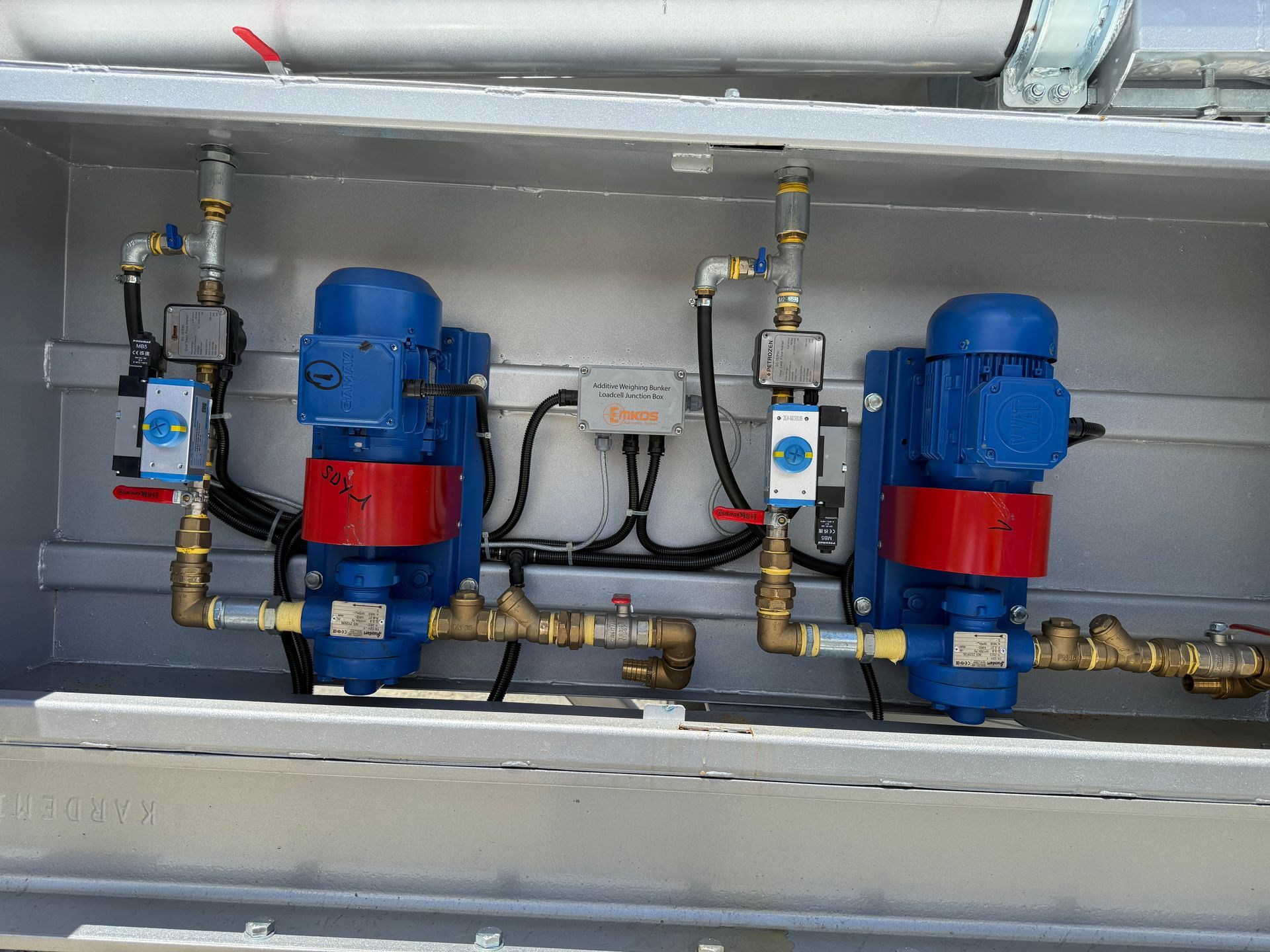 Two blue electric pumps with red bases and brass plumbing, installed inside a metal cabinet.