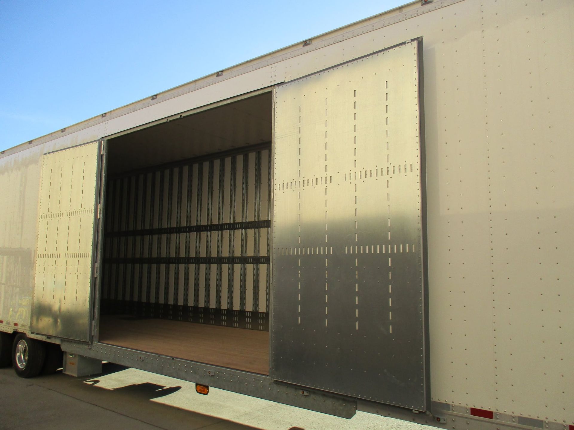 Open shipping trailer with large sliding doors and empty cargo interior