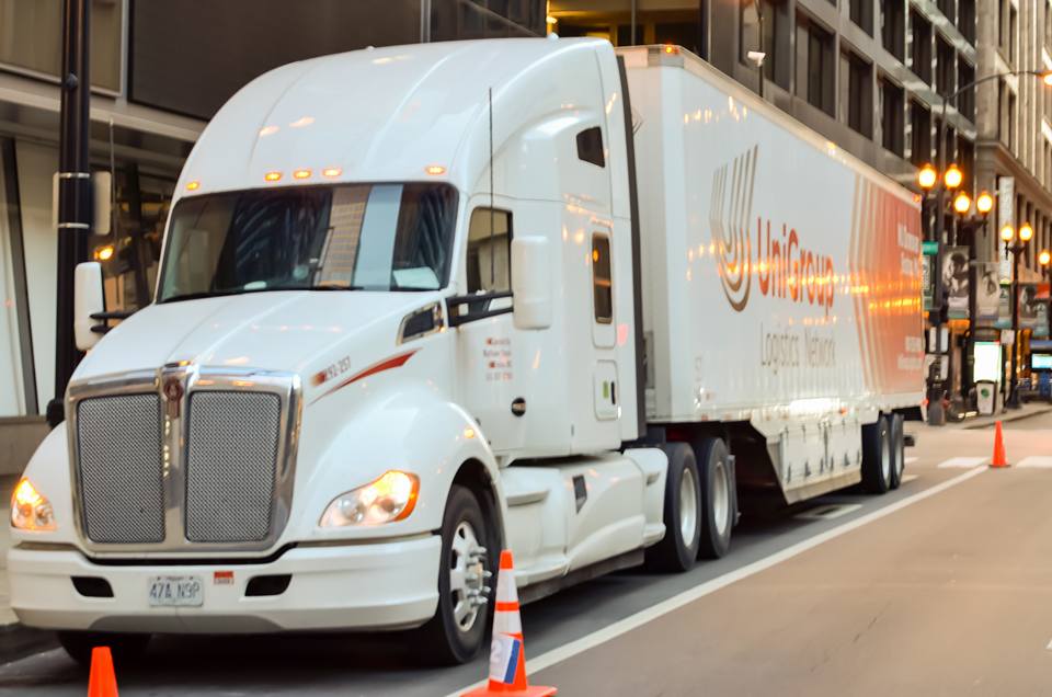 White semi-truck parked on a city street with orange cones beside it