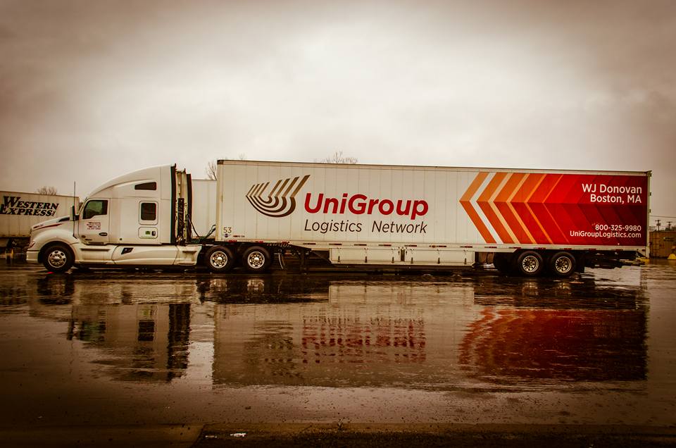 UniGroup logistics semi-truck parked on a wet road in a sepia-toned scene