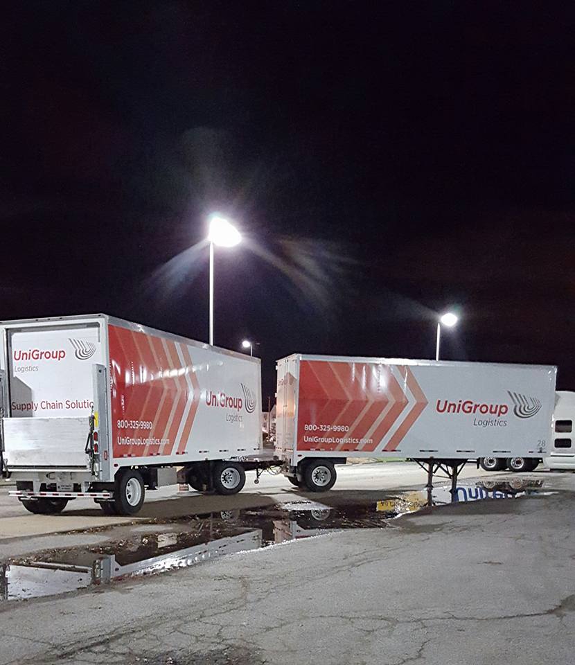 Two UniGroup moving trailers parked at night under bright lot lights
