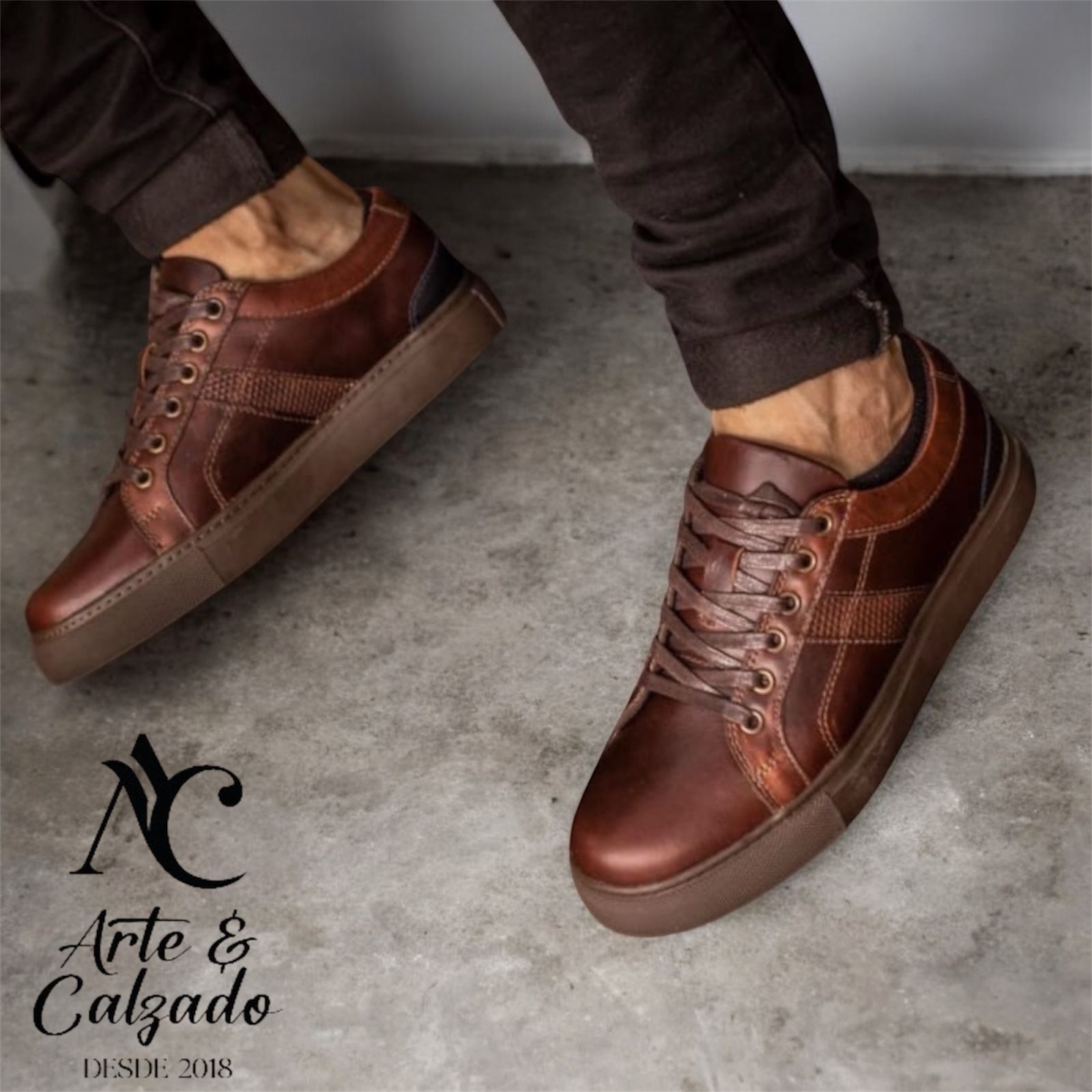 Zapatillas deportivas informales de cuero marrón puestas sobre un suelo de hormigón gris