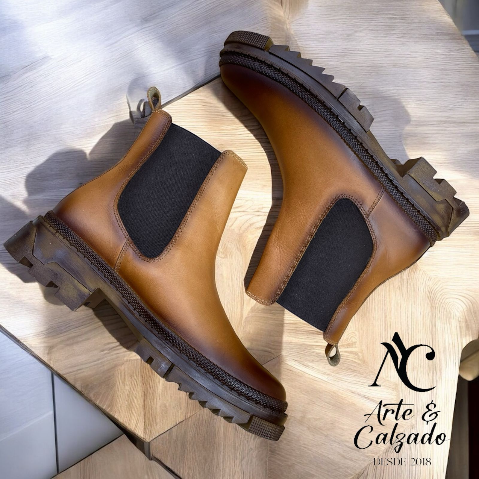 Un par de botines Chelsea de cuero marrón con paneles laterales elásticos negros y suelas gruesas con relieve