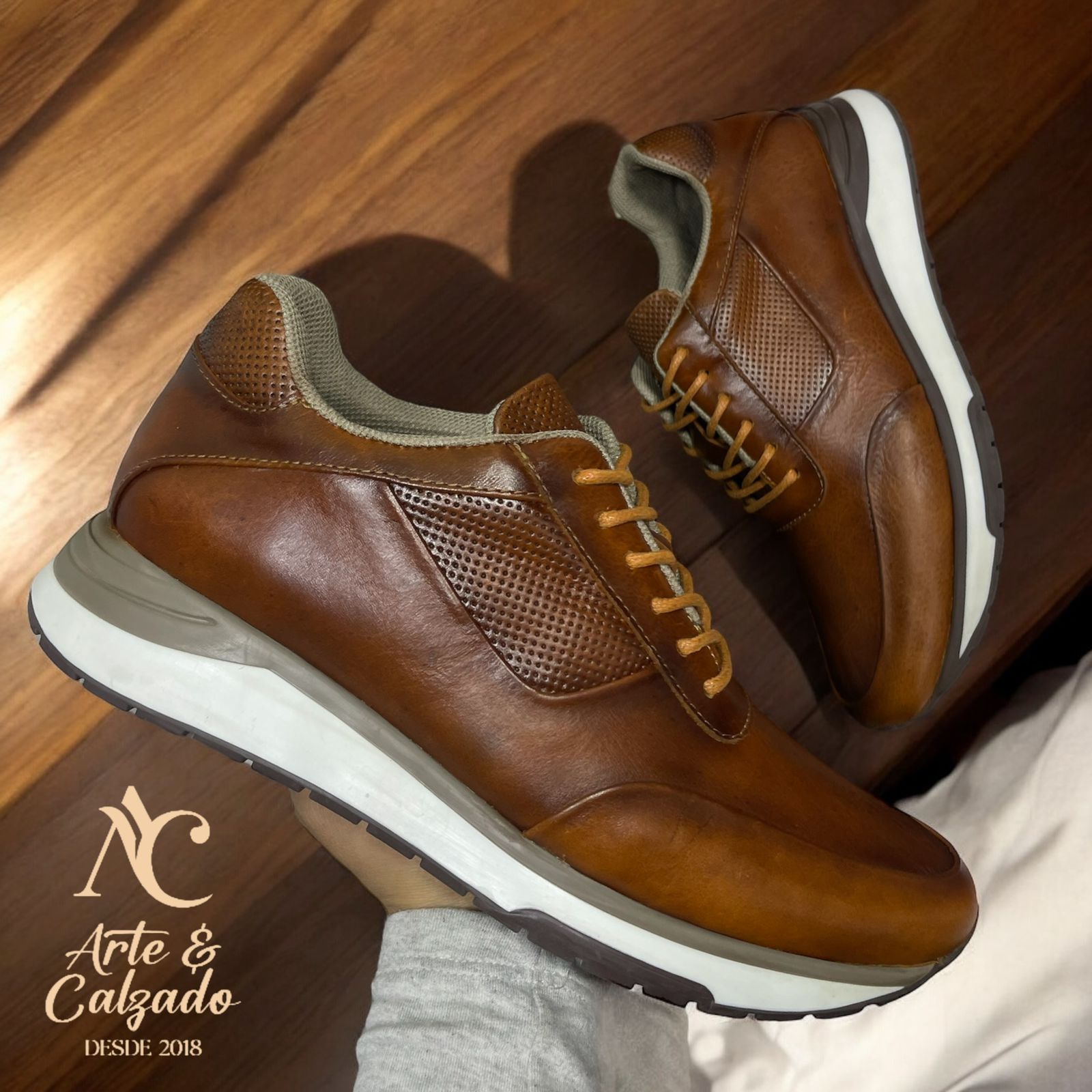 Un par de zapatillas deportivas de piel marrón con paneles laterales perforados y suelas blancas