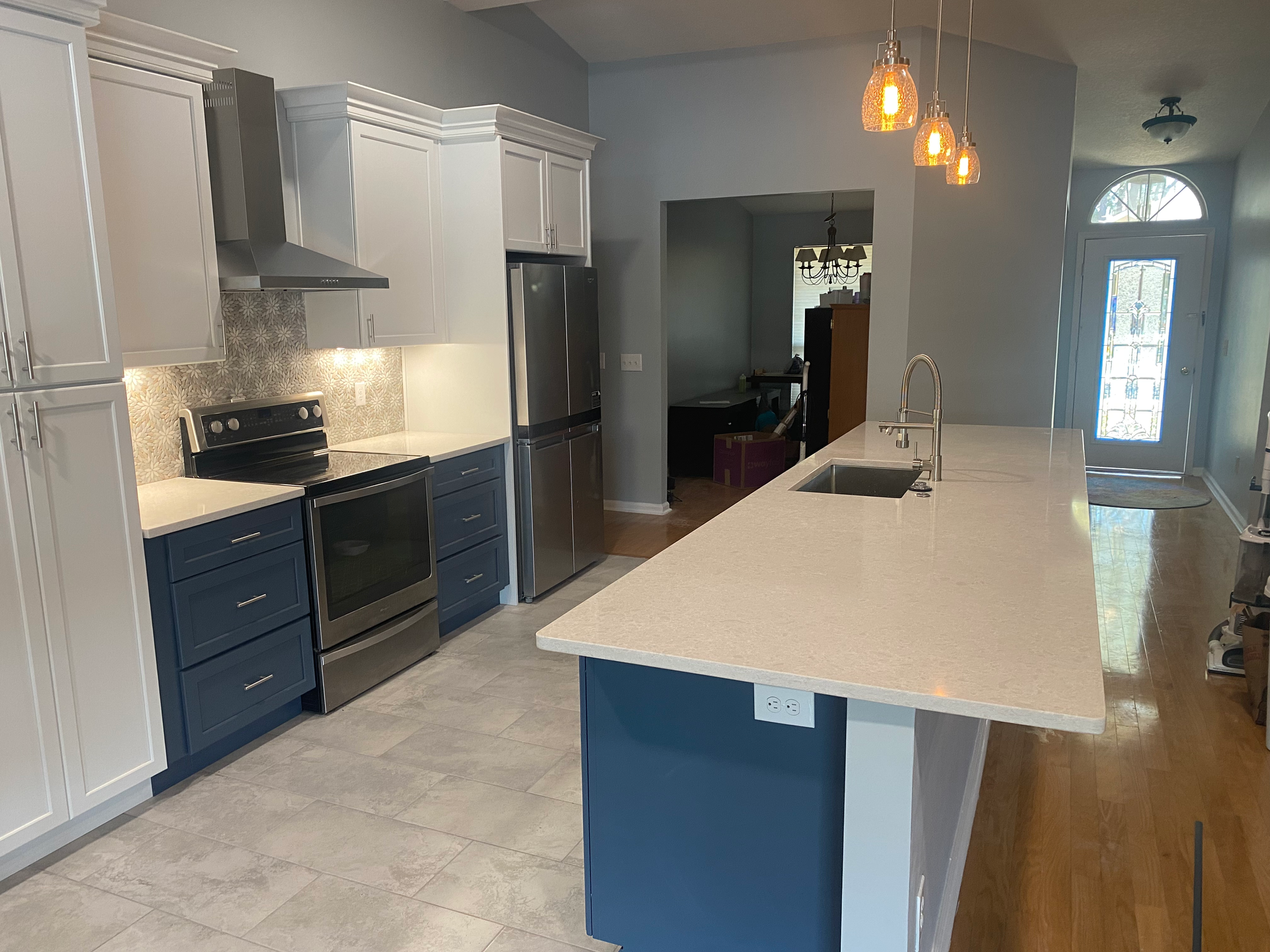 Modern kitchen with blue and white cabinets, stainless steel appliances, and a long island.