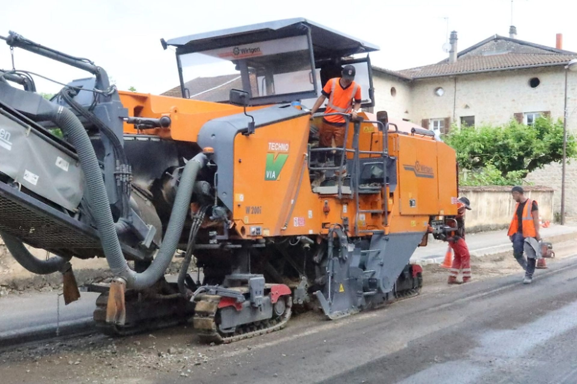 Orange asphalt paving machine lays new blacktop on a local street during Asphalt Paving Services in College Station, TX.