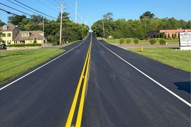 Freshly resurfaced road with yellow center lines after Asphalt Paving Services in College Station, TX by suburban homes.