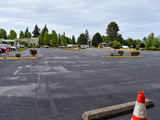 Wide parking lot has new asphalt and traffic cones after Asphalt Paving Services in College Station, TX on a cloudy day.