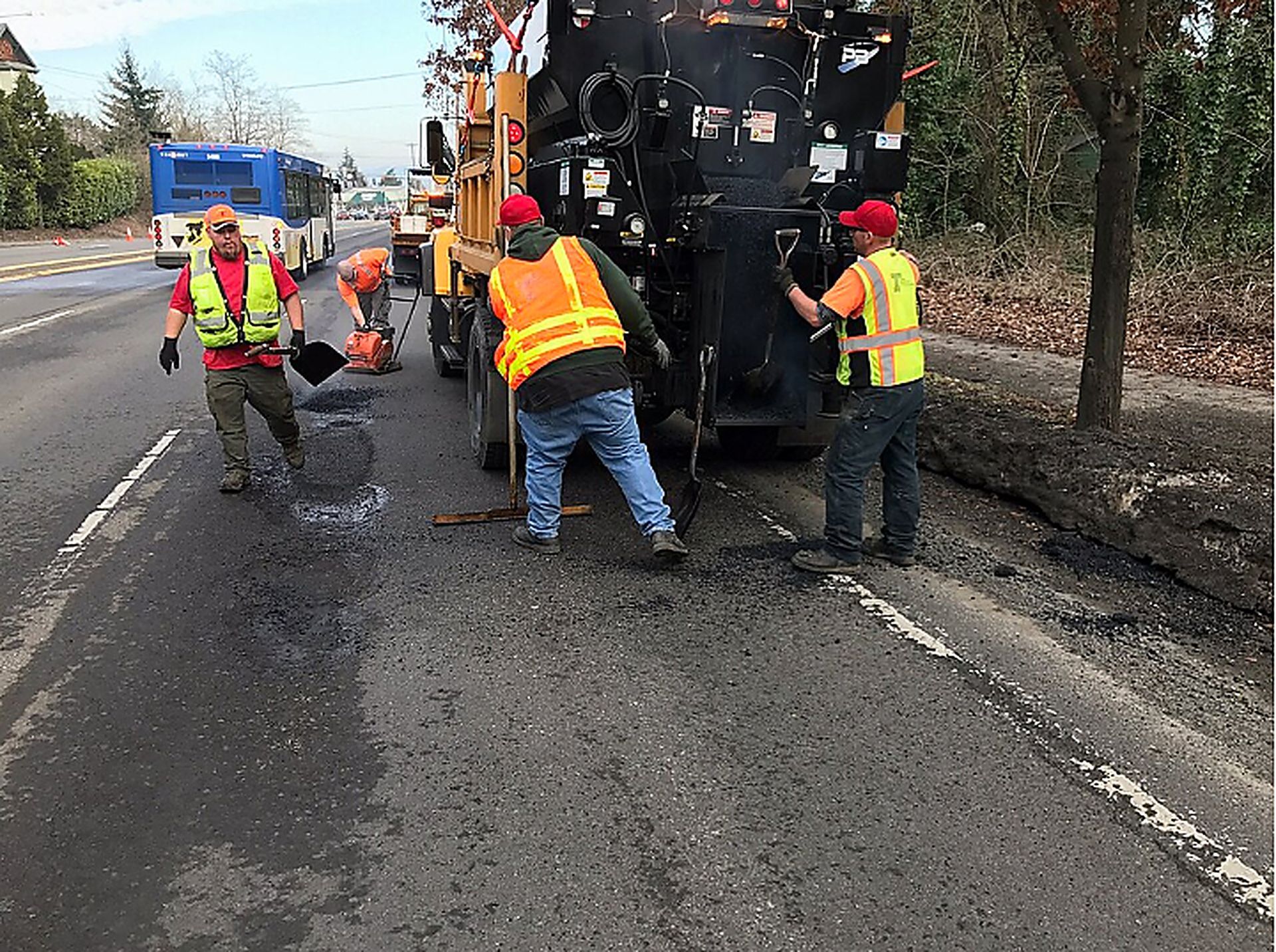 Crew spreads fresh asphalt beside a dump truck during Asphalt Paving Services in College Station, TX for surface repair.